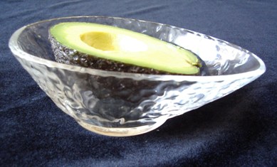 Half an avocado in a glass avocado dish.